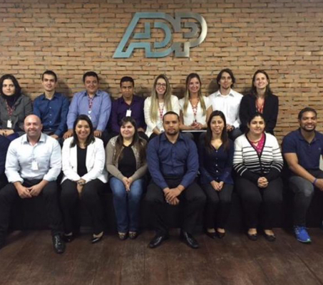 two rows of associates seated below an ADP sign