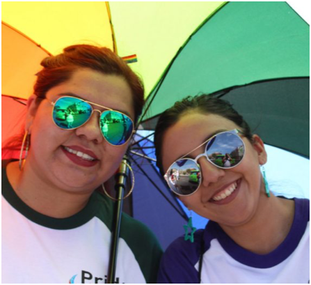 two female ADP associates sharing a rainbow-colored umbrella