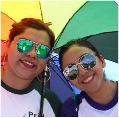 two female ADP associates sharing a rainbow-colored umbrella