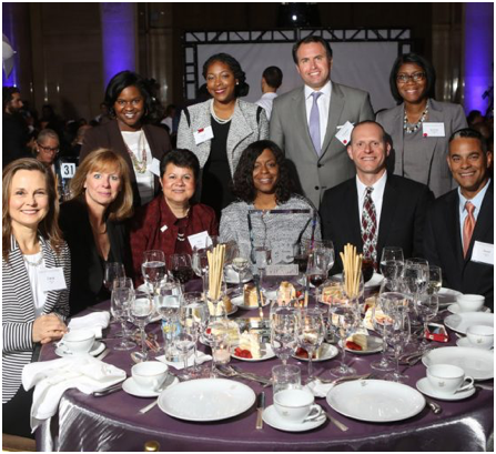 group of ADP associates seated and standing around a formal dinner table