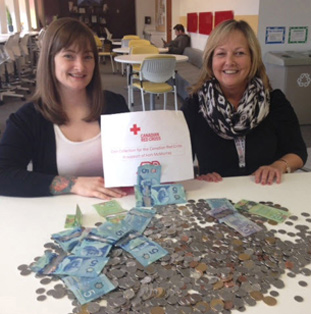 two volunteer ADP associates seated at a table covered with monetary donations to the Canadian Red Cross