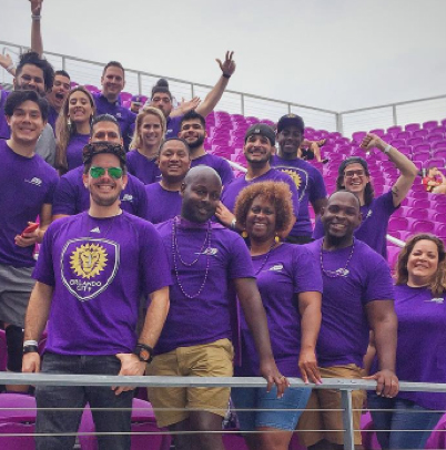 large group of ADP associates in purple t-shirts standing in stadium stands