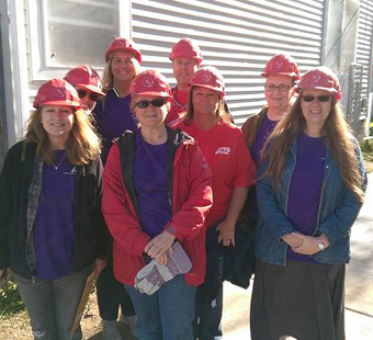 group of ADP associates wearing purple T-shirts and red construction hardhats