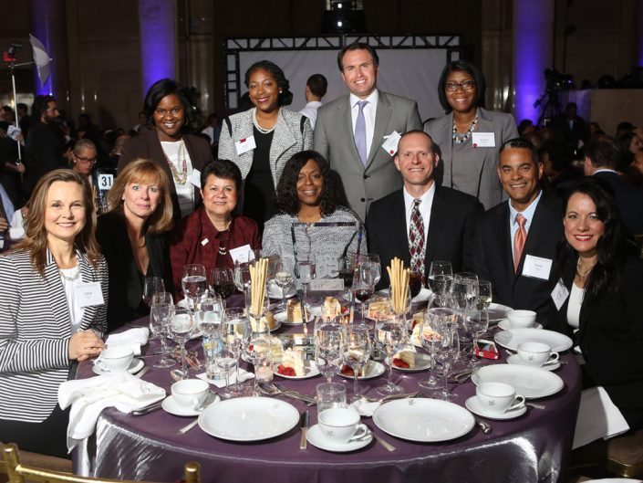 zaměstnanci ADP sedící a stojící kolem stolu při udílení cen